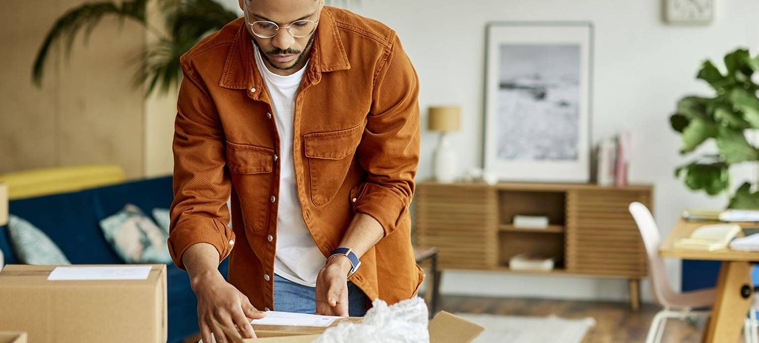 Homme préparant des cartons de déménagement dans un salon