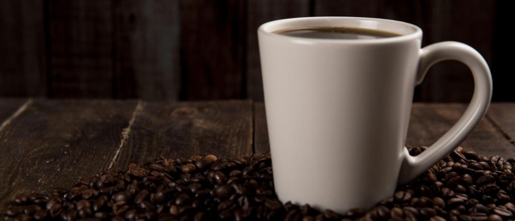 Tasse de café entourée de grains disposés sur une table en bois