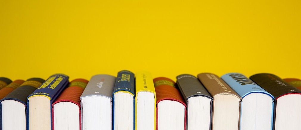 Rangée de livres scolaires alignés devant un fond jaune