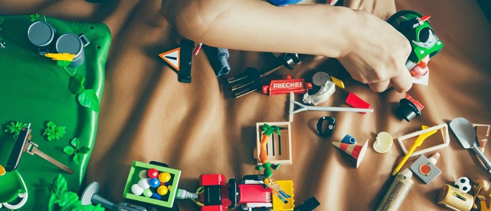 Enfant manipulant des jouets d’éveil posés sur un tissu