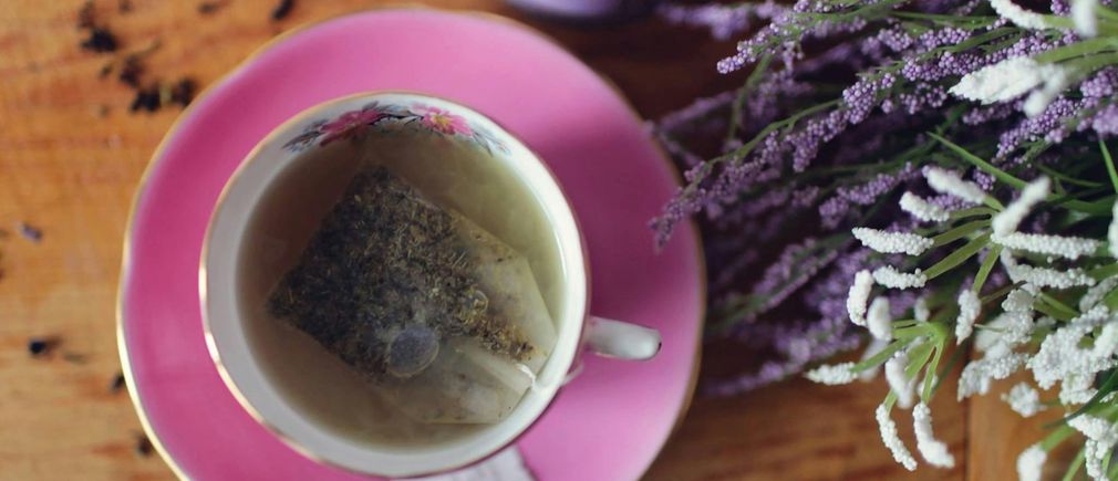 Tasse de thé posée sur soucoupe avec sachet et décor floral