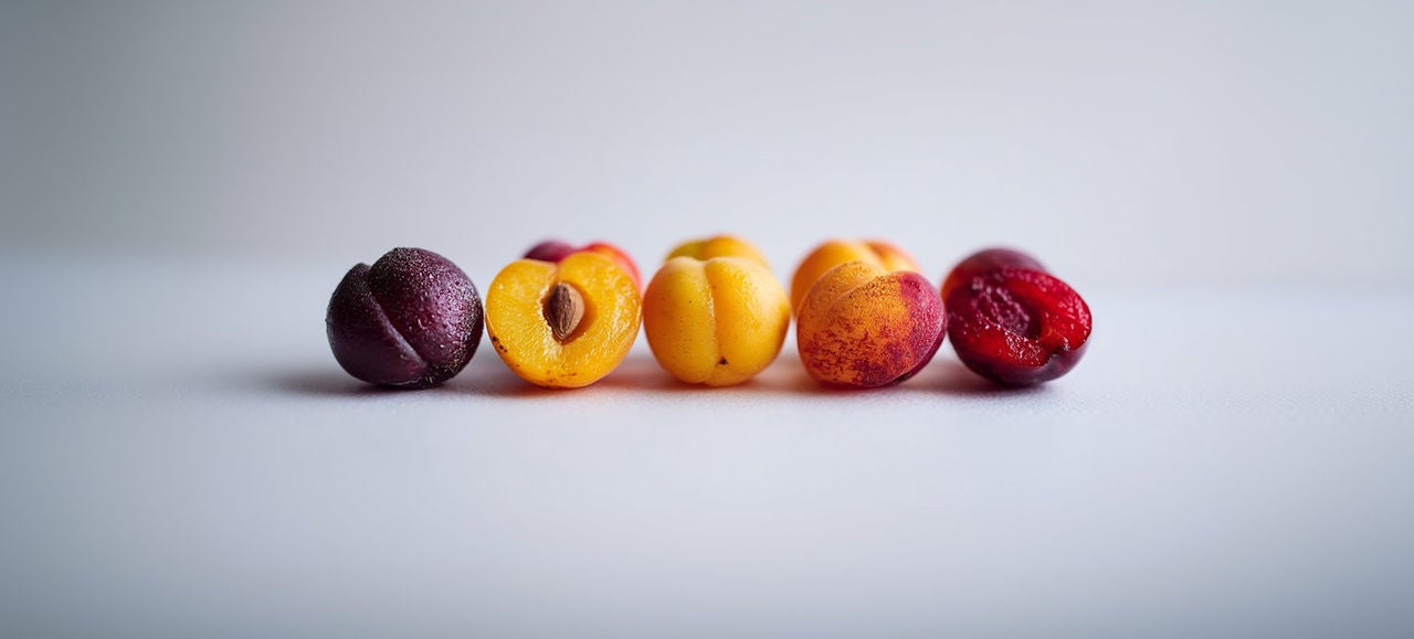 Los albaricoques enteros y las mitades con piedras se alinean sobre un fondo blanco.    Generado con IA