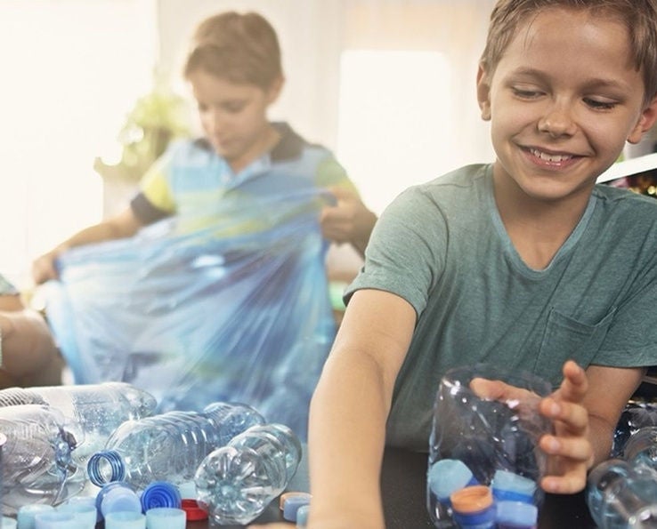 Enfants triant des déchets plastiques et en carton avec un sac poubelle Handybag