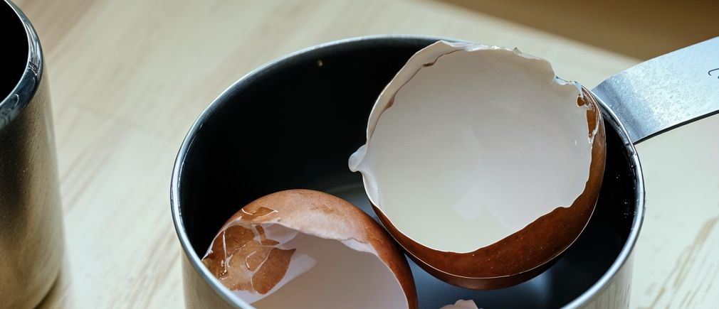 Coquilles d’œufs cassées dans une casserole posée sur une planche en bois
