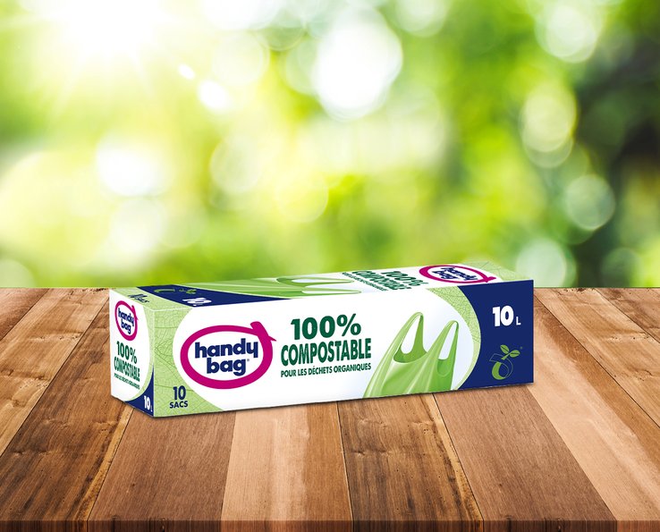 Caja de bolsas de basura Handybag compostables 10 litros sobre una mesa de madera con fondo vegetal desenfocado